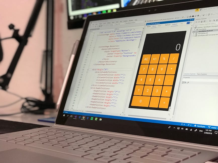 A close-up view of a laptop with a white keyboard displaying a code editor on the screen, showing lines of HTML or CSS code in various colors alongside a large orange calculator interface with numeric